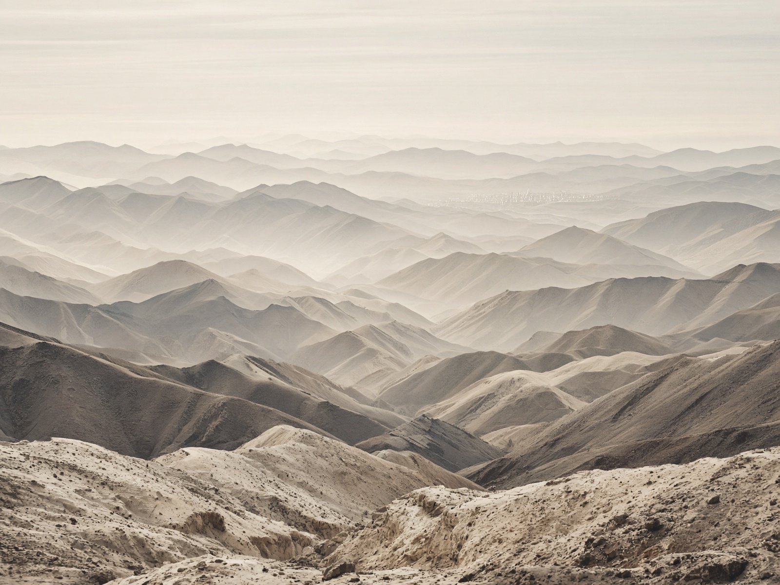 Successive mountain ridges in dust light, a long road implied.